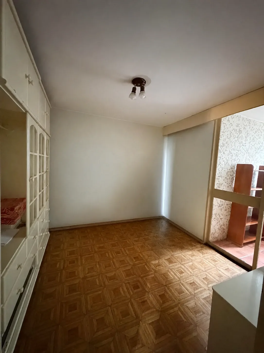 Quarto com armários, piso de madeira e acesso à varanda interna