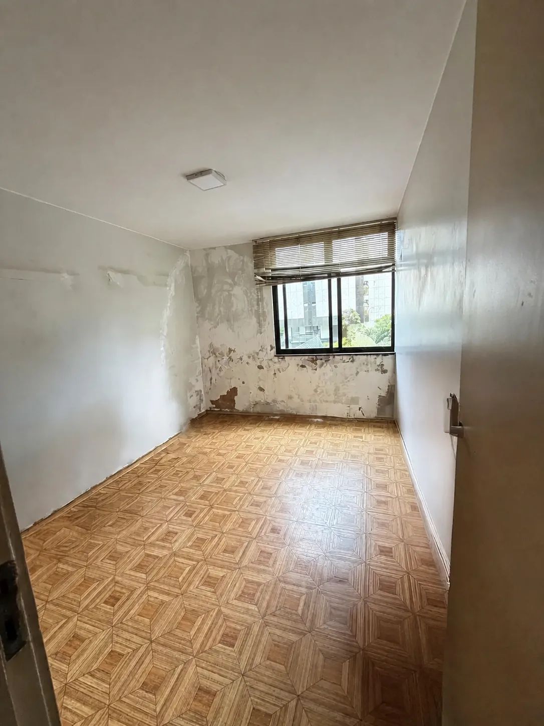 Quarto vazio com piso de madeira e parede que requer atualização